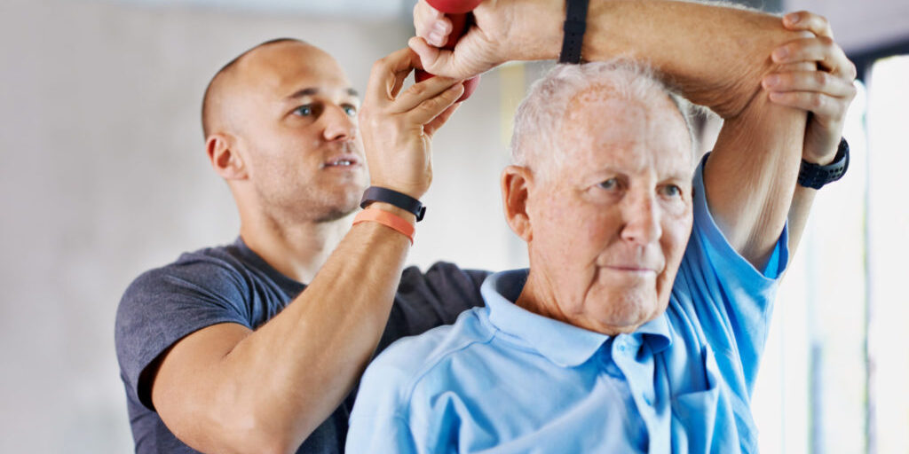 Shot of a physiotherapist helping a senior man with weights